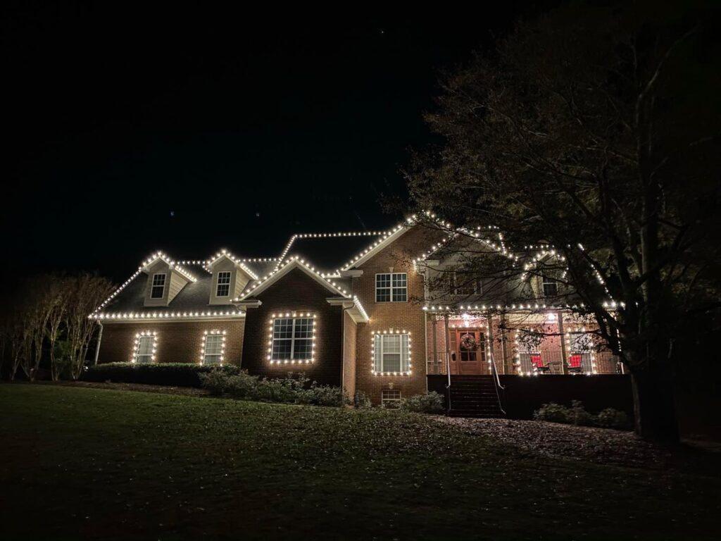 Home with lit windows and roofline lights at night