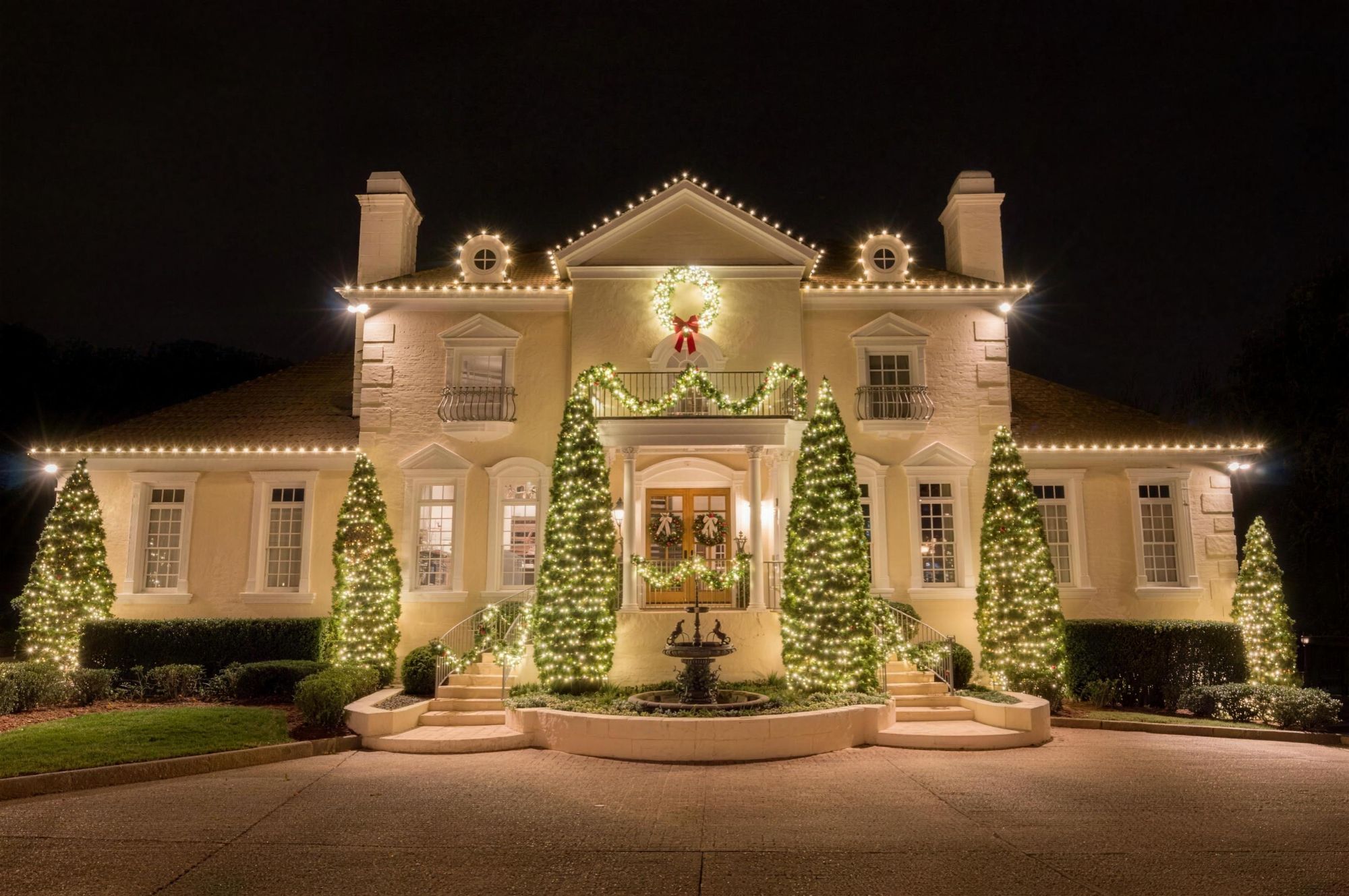 Stone home glowing with holiday lights at night